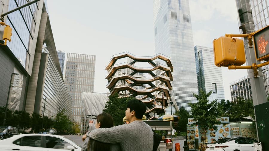 A man and his date, a woman, seen from behind as they look up at the Vessel in New York's Hudson Yards.